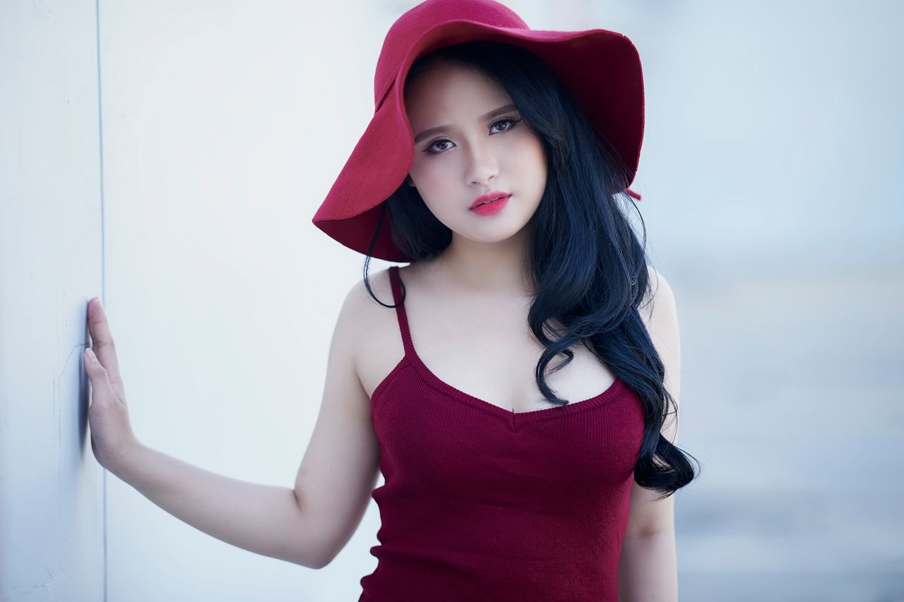 stylish woman in a red hat and dress posing outdoors exuding elegance