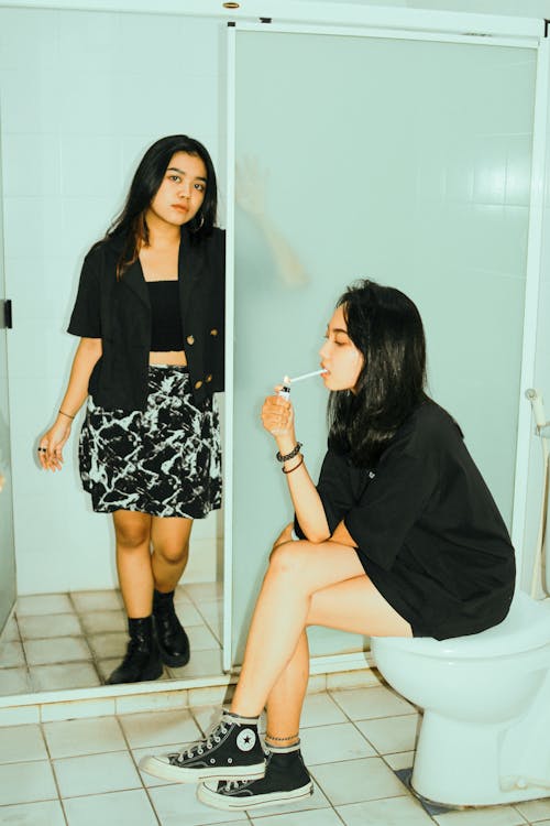 A Girl in Black Shirt Lighting Cigarette in Comfort Room