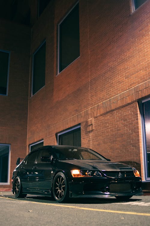 A Black Car Parked Beside Brown Brick Wall