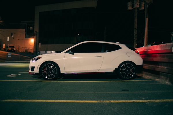 White coupe parked on a city street at night, photo by Erik Mclean on Pexels