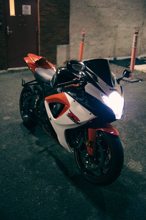 Free Close-up of a parked sport motorcycle at night with a bright headlight illuminating the scene. Stock Photo