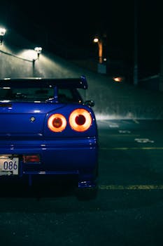 A stunning blue sports car parked at night, showcasing bright, illuminated taillights.
