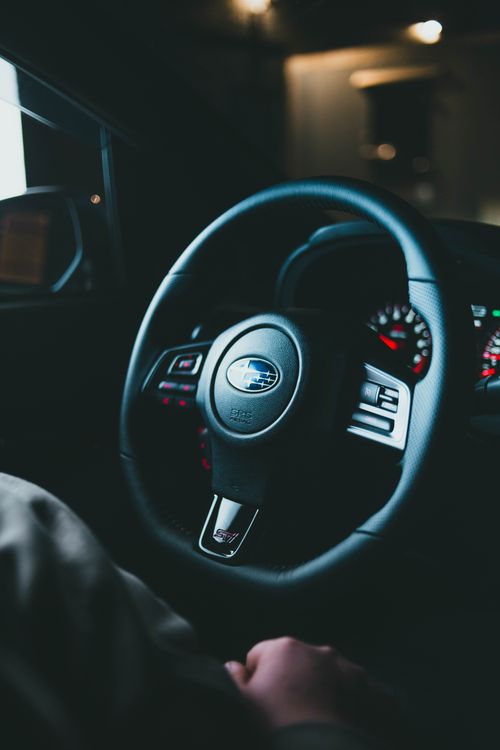 Free Dimly lit close-up of a steering wheel inside a car, emphasizing its design and details. Stock Photo