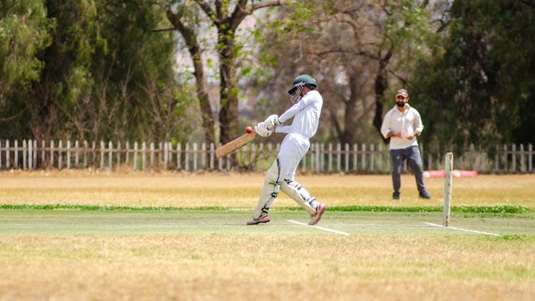 Person In White Pants And White Long Sleeves Holding A Cricket Bat