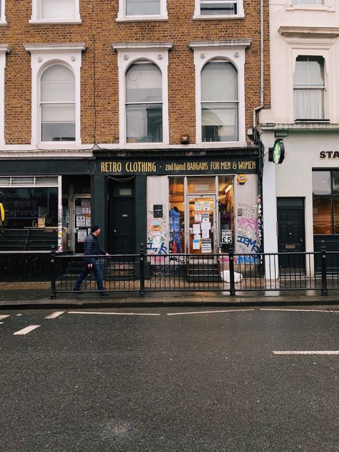 Exterior of a retro clothing shop on a rainy London street, showcasing urban life and fashion.