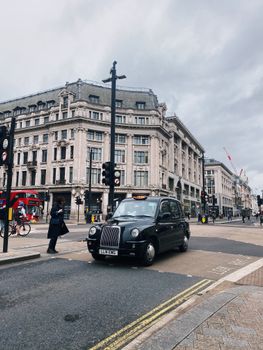 Black London taxi navigating Oxford Circus amidst historic architecture.