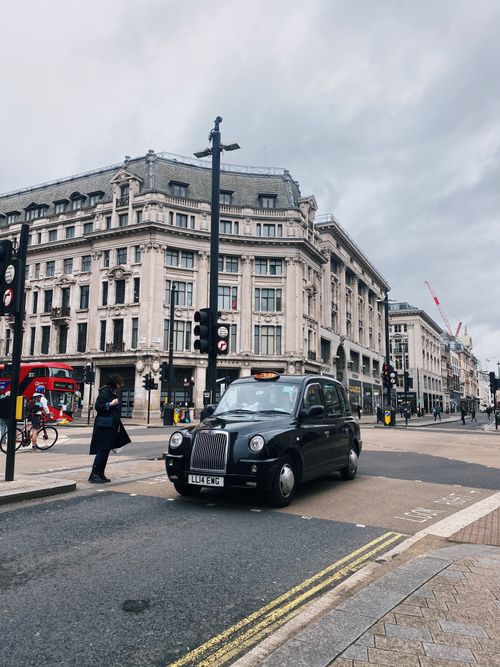 Free Black London taxi navigating Oxford Circus amidst historic architecture. Stock Photo