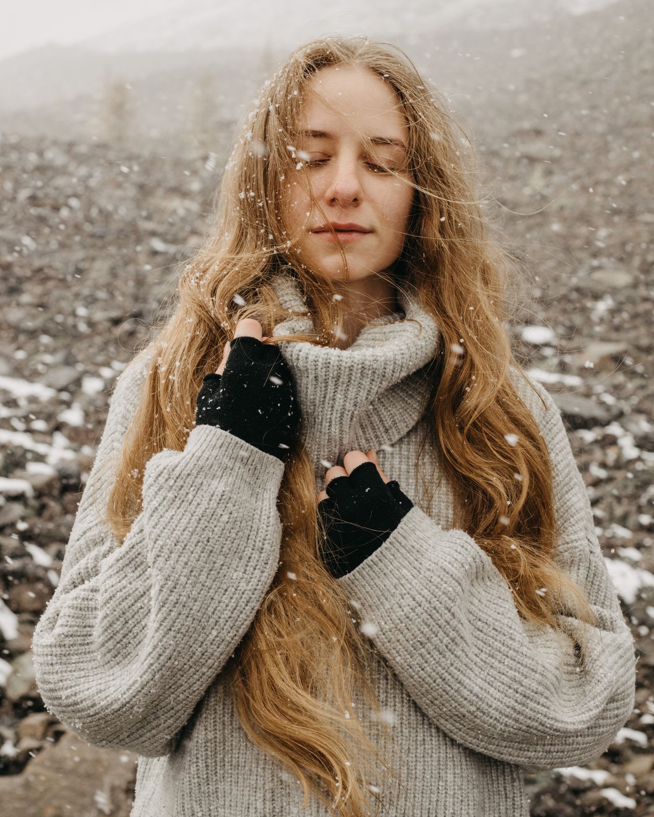 Woman in a grey turtleneck sweater and fingerless gloves