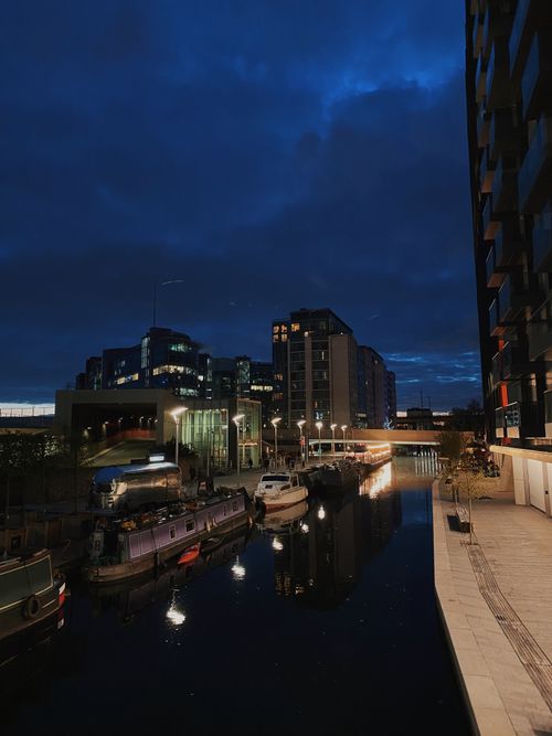 Free Serene canal view of boats and urban cityscape in London at dusk. Stock Photo