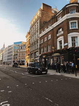 A bustling London street scene featuring classic architecture, a black taxi, and people enjoying an evening out.