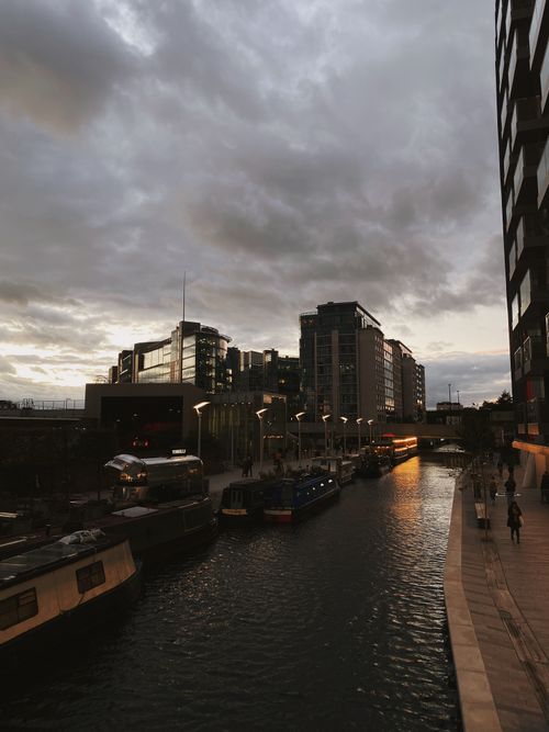 Free Dramatic view of a London canal at sunset, featuring modern architecture and moody skies. Stock Photo