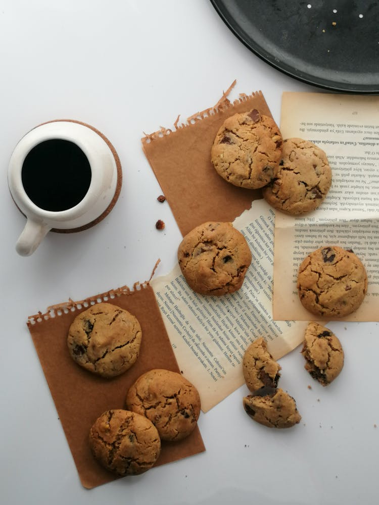 Cup Of Coffee And Cookies Scattered On Paper Sheets