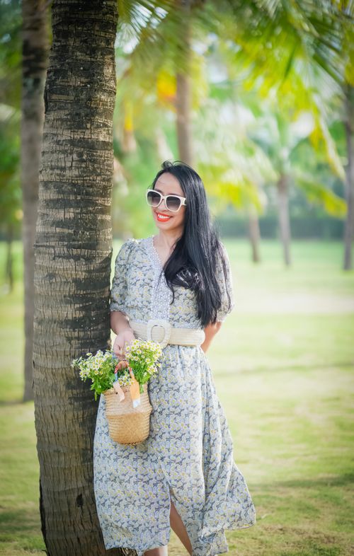 Free Smiling woman in floral dress with flowers in garden, perfect for lifestyle imagery. Stock Photo