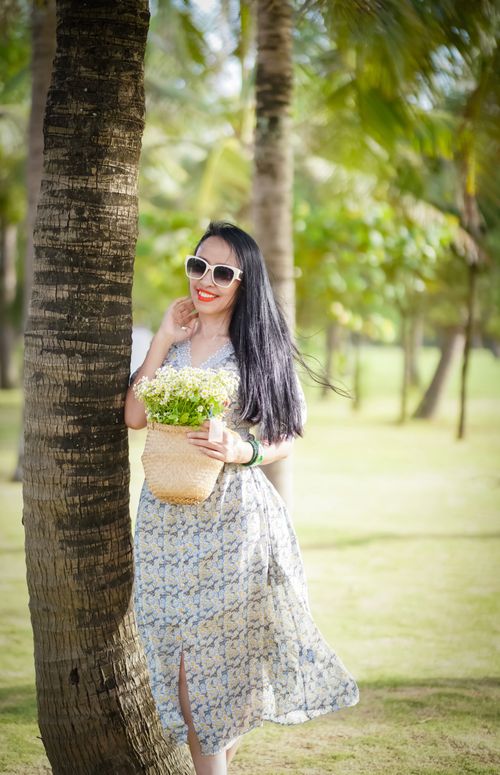 Free Woman in summer dress and sunglasses holding a flower basket outdoors. Stock Photo