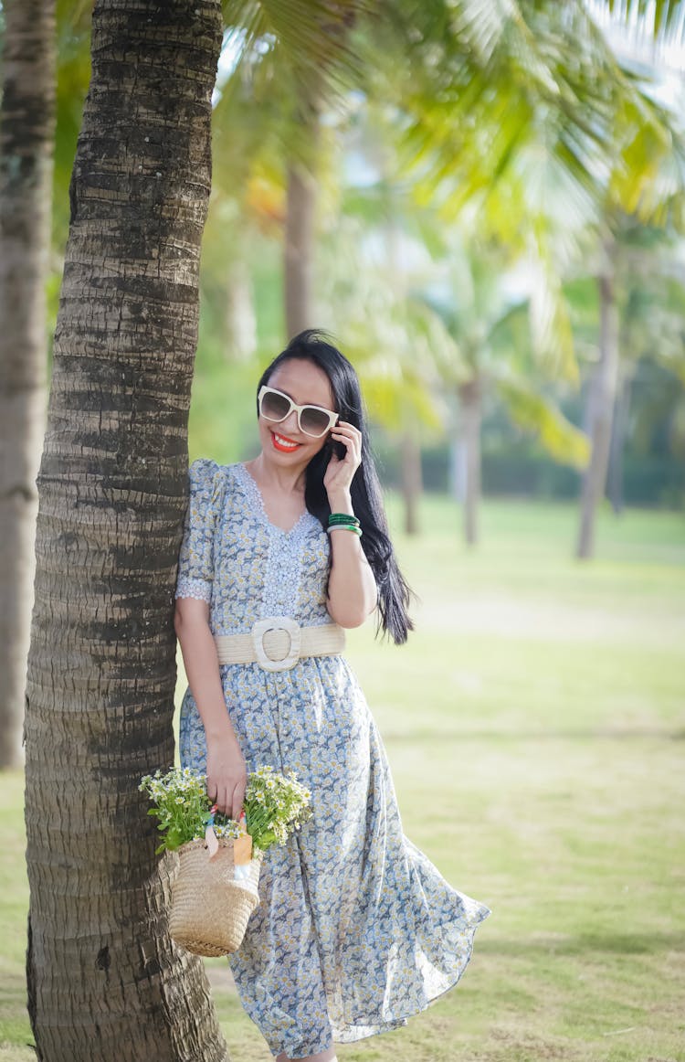 Smiling Brunette Woman In Summer Dress Standing Under Palm Tree