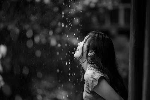 Grayscale Photo of Woman Looking at Rain