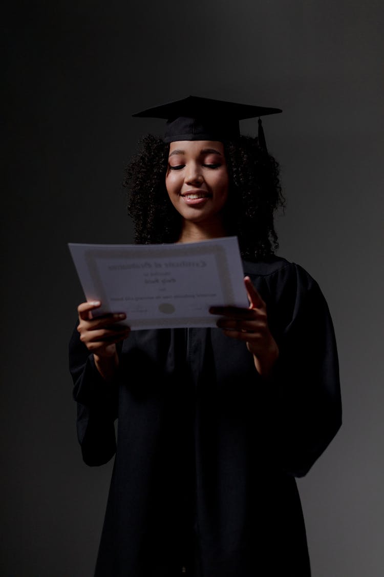 A Black Student Looking At Certificate of Graduation 