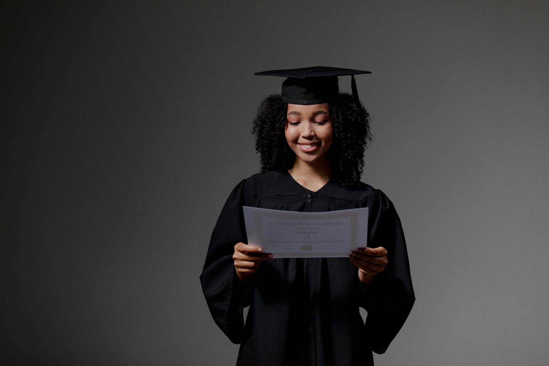 Curly-haired graduate student holding certificate