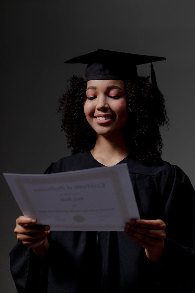 A Black Female student Looking At certificate Of Graduation 