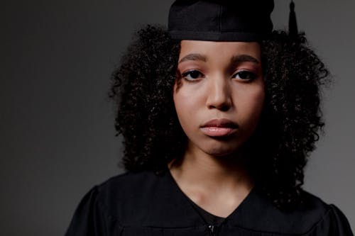 A sad black female student looking at camera and wearing Square academic cap