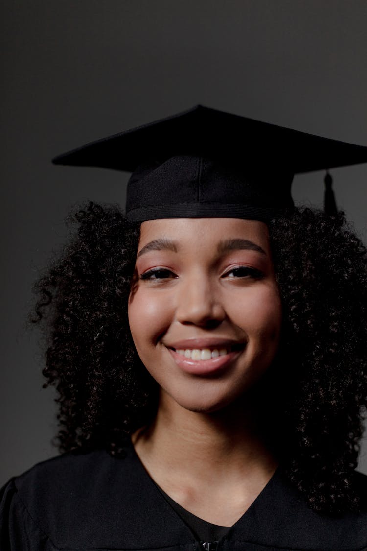 A Close Up On A Black Female Student Looking At Camera And Wearing Square Academic Cap