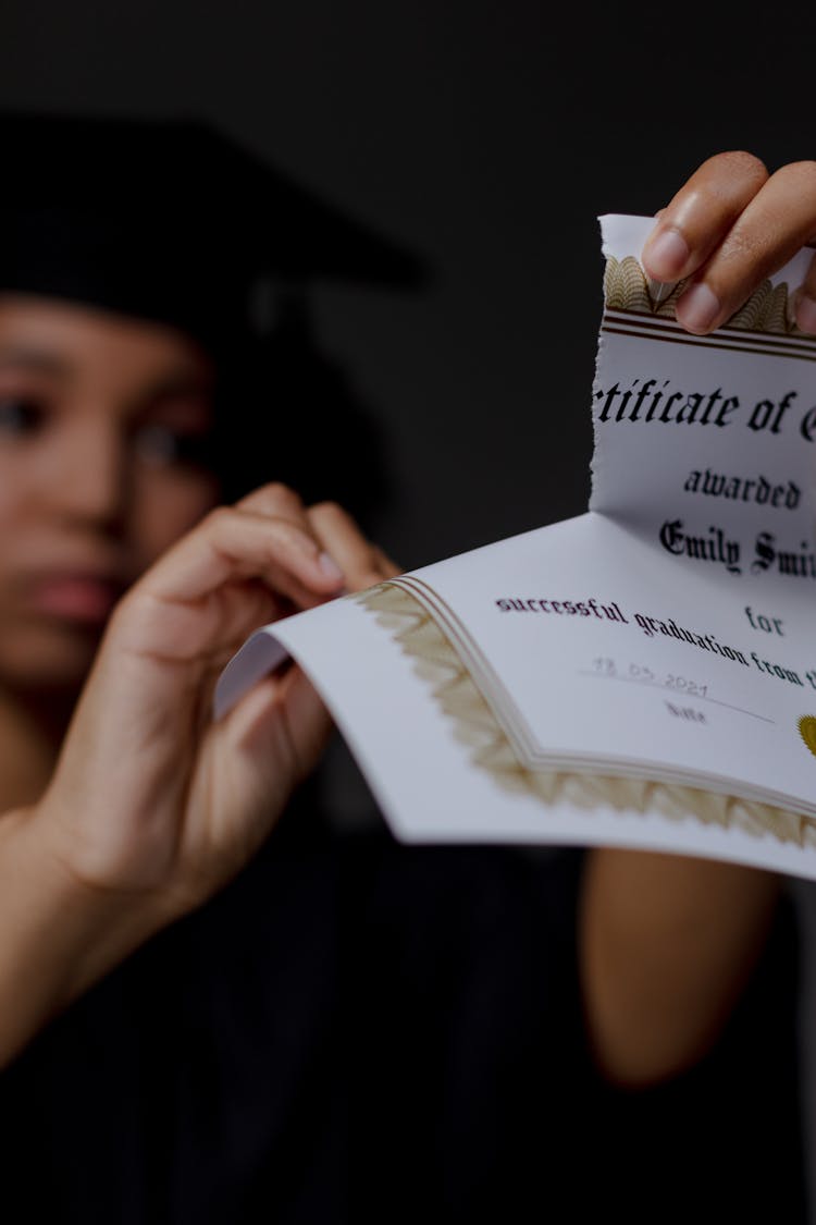 A Black Female Student Tearing Up Certificate Of Graduation