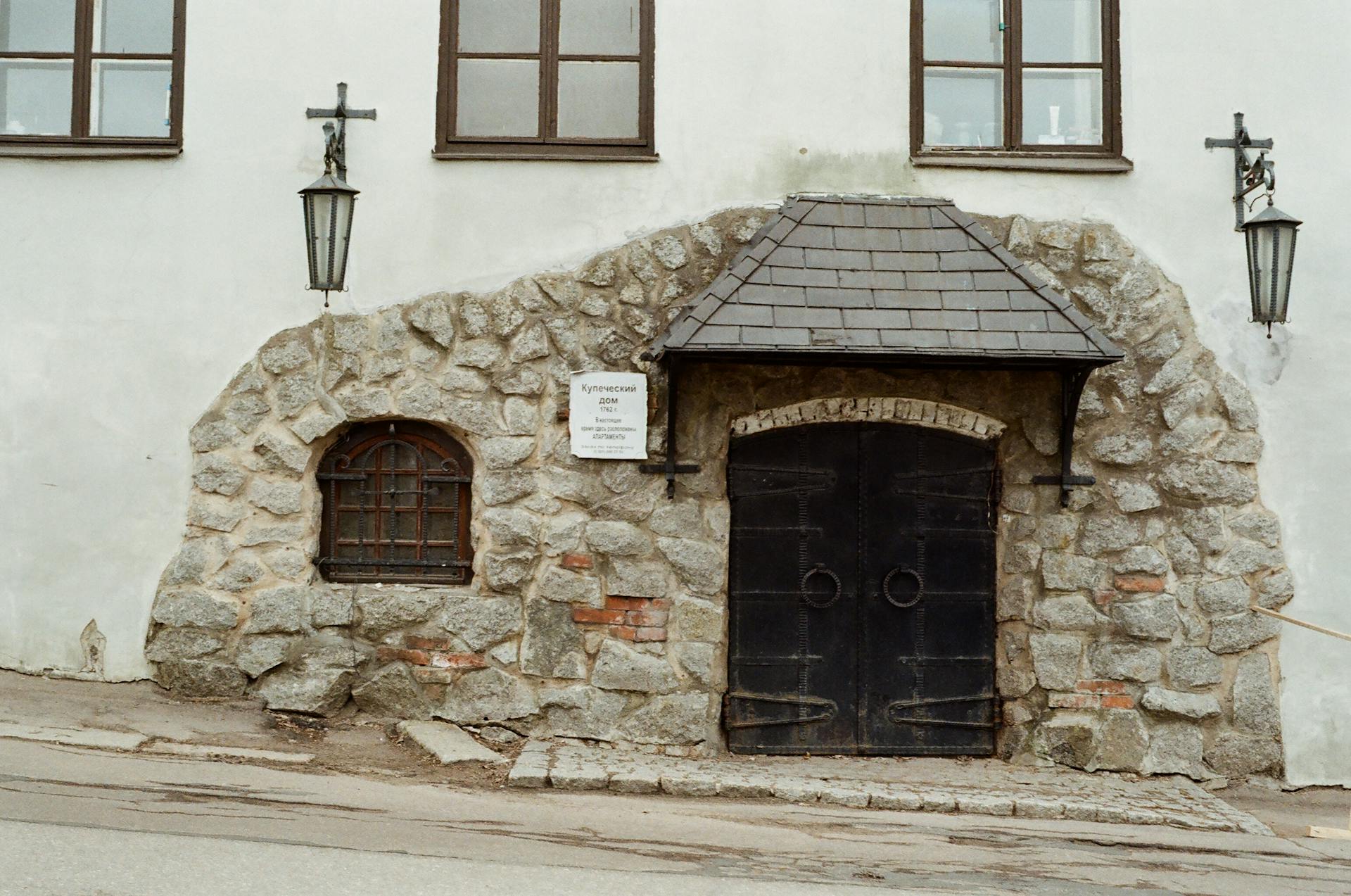 Old stone facade with iron doors and lanterns in Vyborg, Russia, showcasing historical architecture.