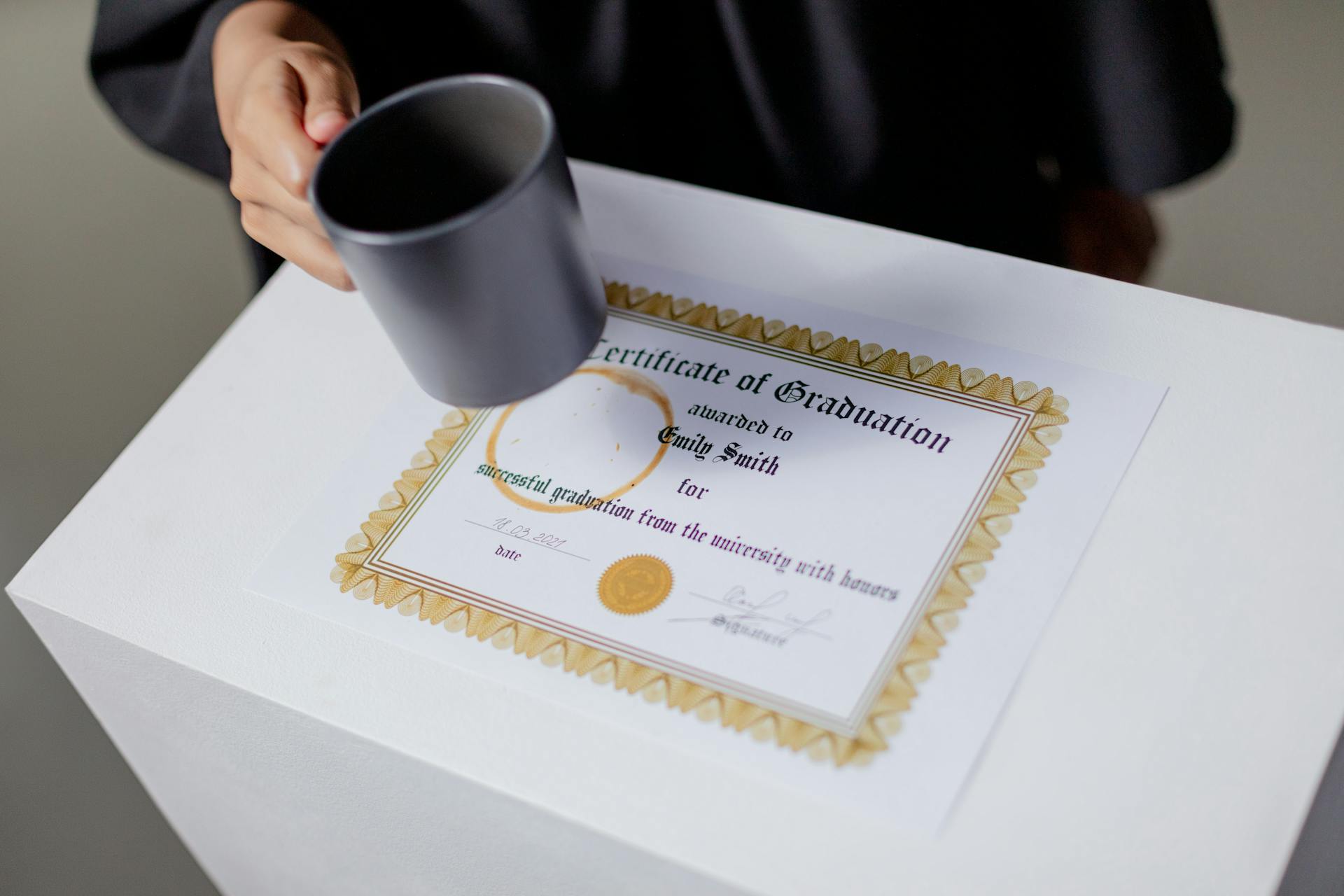 A Person Holding a Mug Near the Certificate on the Table