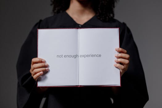 A graduate in cap and gown displays a diploma reading 'not enough experience', highlighting job market challenges.