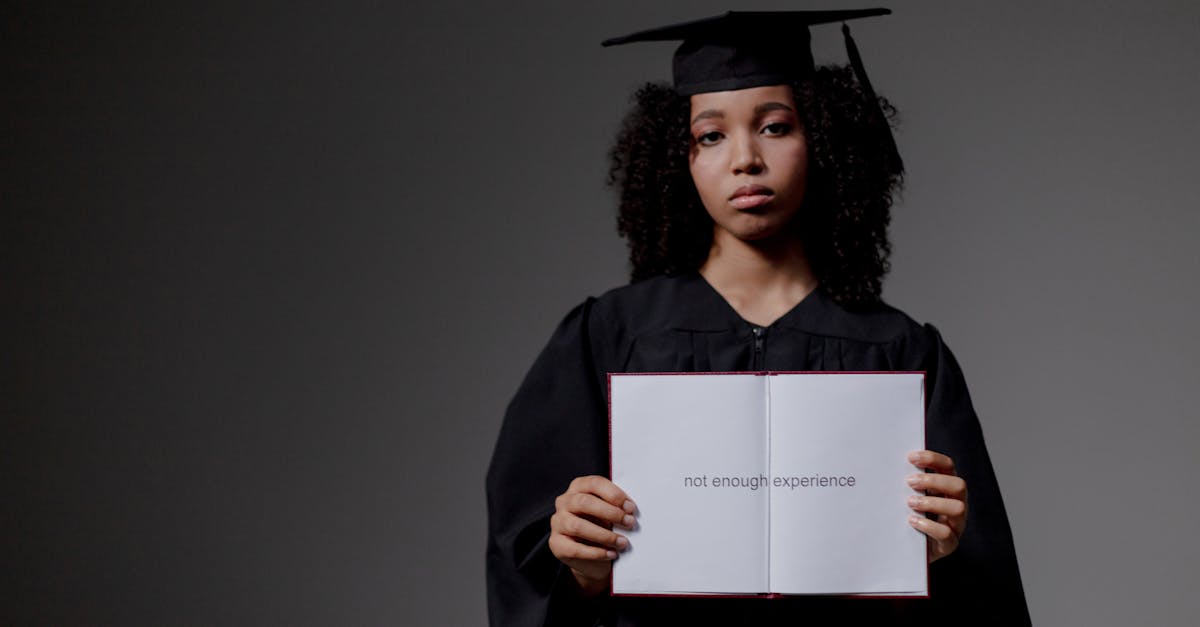 Young graduate holding a book with 'not enough experience' message, symbolizing job hunt difficulties.