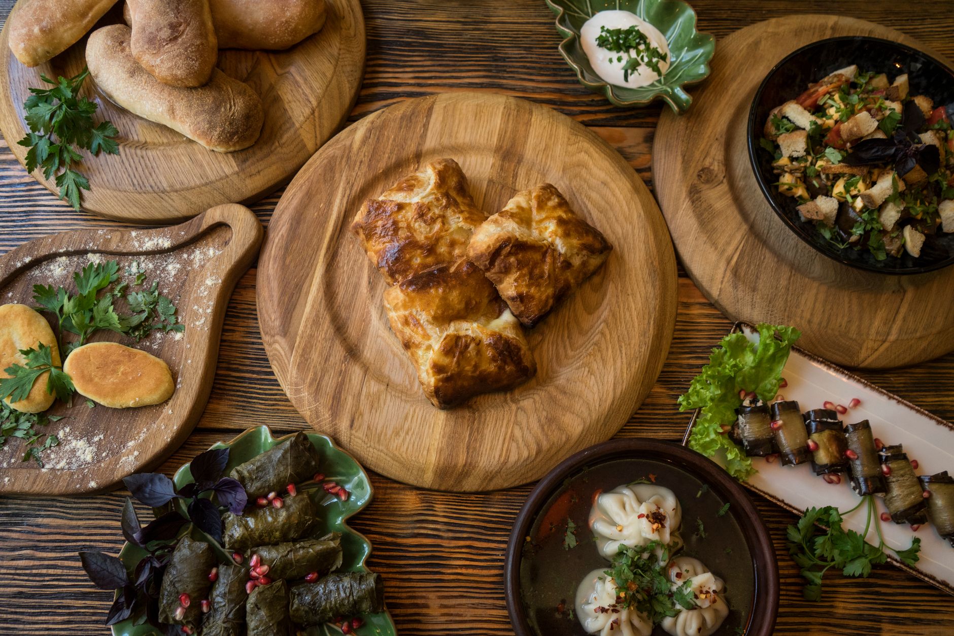 A variety of traditional Georgian dishes displayed on a wooden table with fresh herbs.