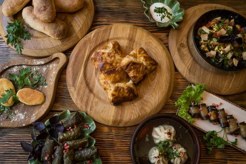 Free A variety of traditional Georgian dishes displayed on a wooden table with fresh herbs. Stock Photo