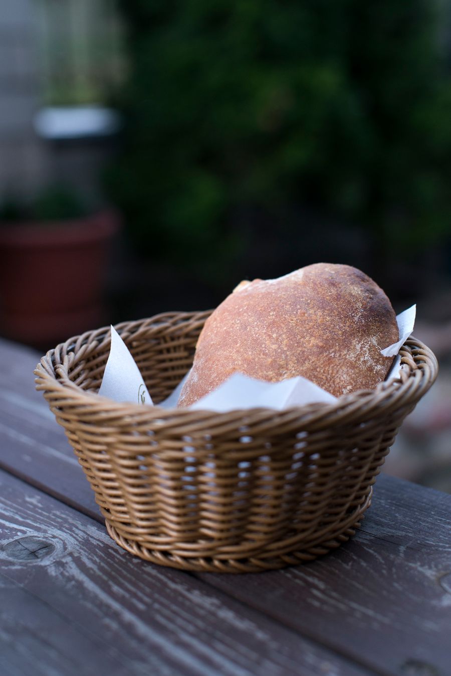 Pain artisanal dans un panier en osier posé sur une table en bois, ambiance conviviale