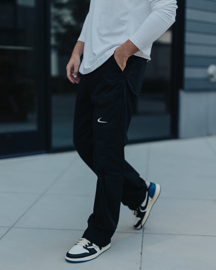 A Man In White Long Sleeves And Black Pants Wearing Blue And White Nike Sneakers