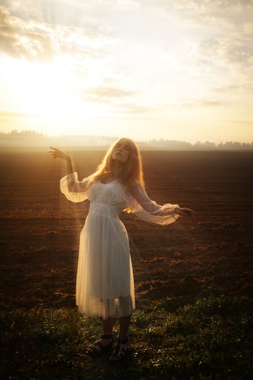 Woman posing in field at sunset