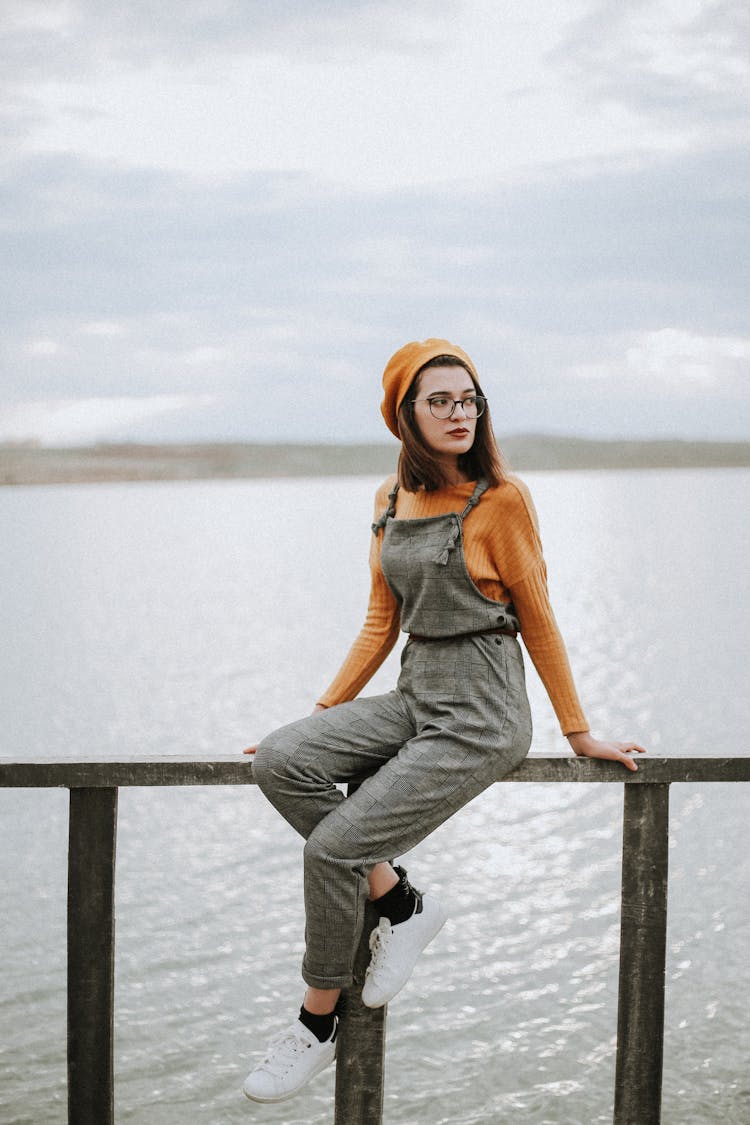 Young Woman Wearing Checkered Dungarees And Beret And Posing