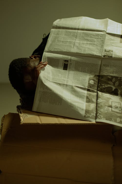 Homeless man covered with newspaper
