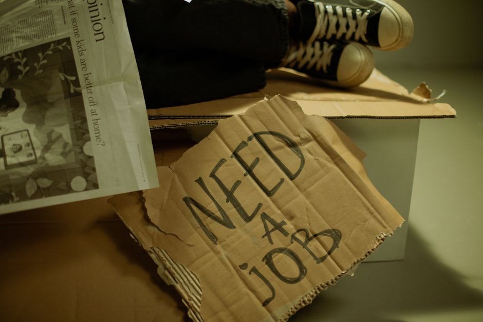 Health Insurance Marketplace vs Employer Coverage: Key Differences Explained Close-up of a cardboard sign and newspaper depicting joblessness and unemployment.