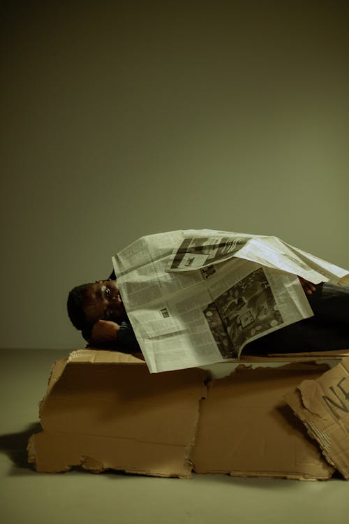 Portrait of homeless man lying on side on cardboard