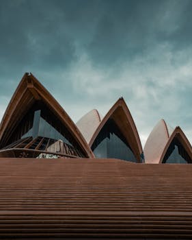 Dramatic view of Sydney Opera House against an overcast sky.