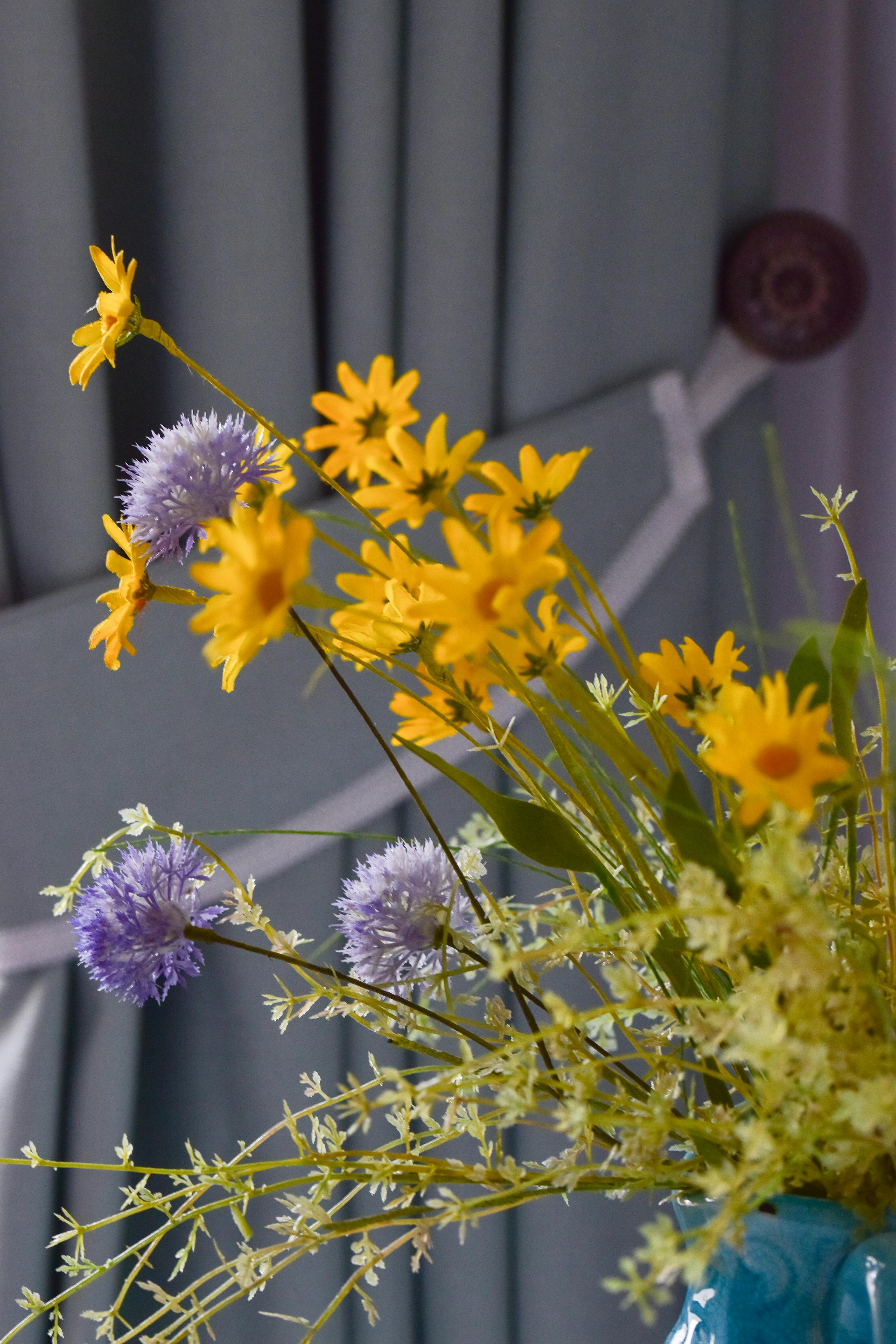 [ColoSach]-a-vivid-bouquet-of-yellow-and-purple-flowers-in-a-blue-vase-against-a-curtain-backdrop.