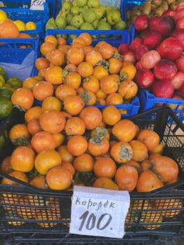 Colorful market stall with fresh persimmons, apples, and pears on display, ideal for food enthusiasts.