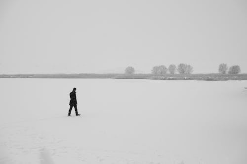 Free Person in Black Jacket Walking on Snow Covered Field Stock Photo