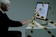 Man typing on computer which is tied with a tape