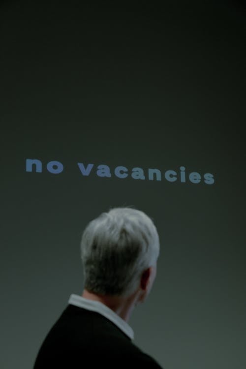Free Elderly man looking at writing saying that there are no vacancies Stock Photo