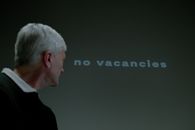 Senior man looking at inscription displayed on wall saying no vacancies