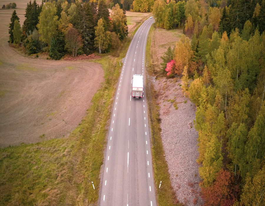 Camion sur une route traversant une forêt, vu du ciel