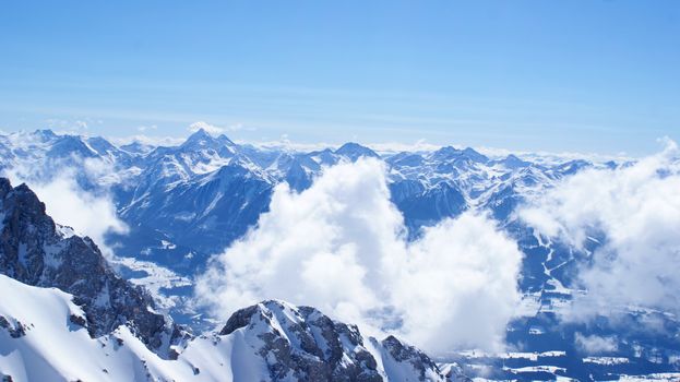 Aerial view of snow-covered Alps in Oberösterreich under a bright blue sky.