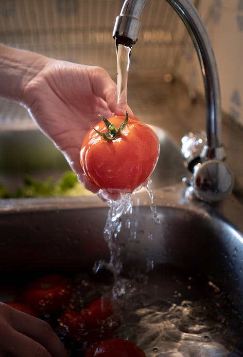 A Person Washing a Tomato