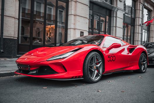Red luxury sports car parked on an urban street, showcasing modern automotive design.